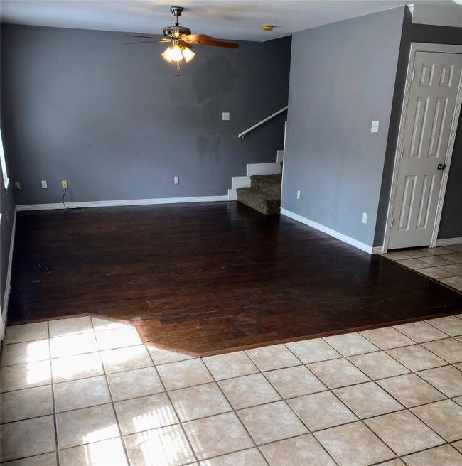 Unfurnished living room featuring baseboards, stairs, ceiling fan, and hardwood / wood-style flooring | Image 11