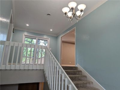 Stairs featuring an inviting chandelier and crown molding | Image 3