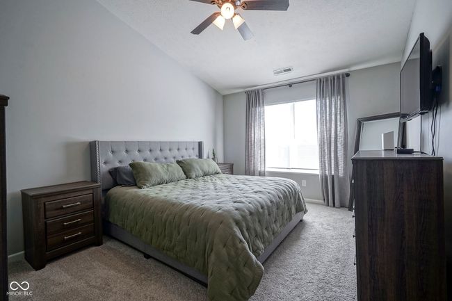 bedroom featuring visible vents, ceiling fan, vaulted ceiling, and light carpet | Image 18
