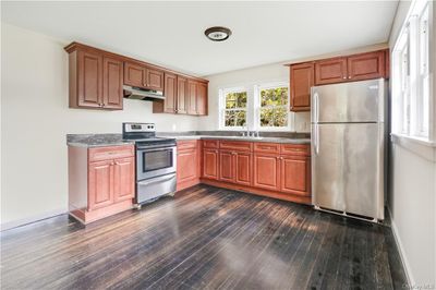 Kitchen with dark stone countertops, appliances with stainless steel finishes, dark hardwood / wood-style floors, and sink | Image 3