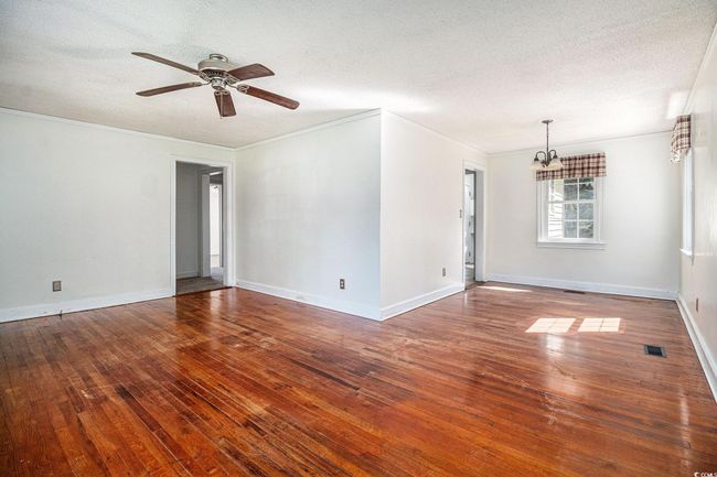 Spare room featuring hardwood / wood-style flooring, ceiling fan, a textured ceiling, a chandelier, and ornamental molding | Image 7