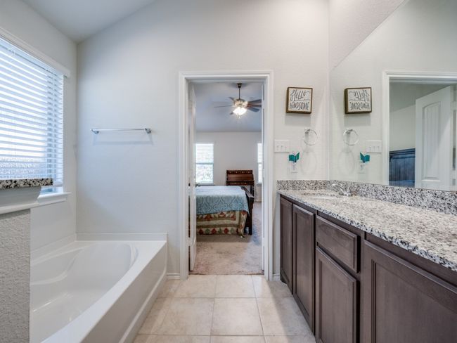 Ensuite bathroom featuring vanity, a bath, ceiling fan, tile patterned floors, and lofted ceiling | Image 20