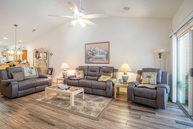 Living area featuring a chandelier, wood finished floors, a ceiling fan, recessed lighting, and high vaulted ceiling | Image 12