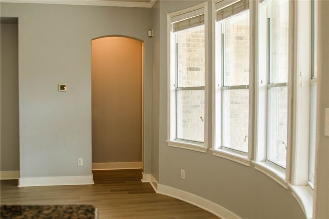 Empty room with arched walkways, plenty of natural light, wood finished floors, and crown molding | Image 17