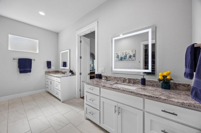 Luxurious spa-like ensuite boasts a deep soaking tub, spacious glass enclosed shower, dual vanities with additional cabinet storage and illuminated, anti-fog mirrors. | Image 22