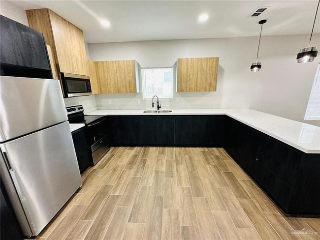 Kitchen with stainless steel appliances, a sink, modern cabinets, dark cabinetry, and light brown cabinets | Image 6