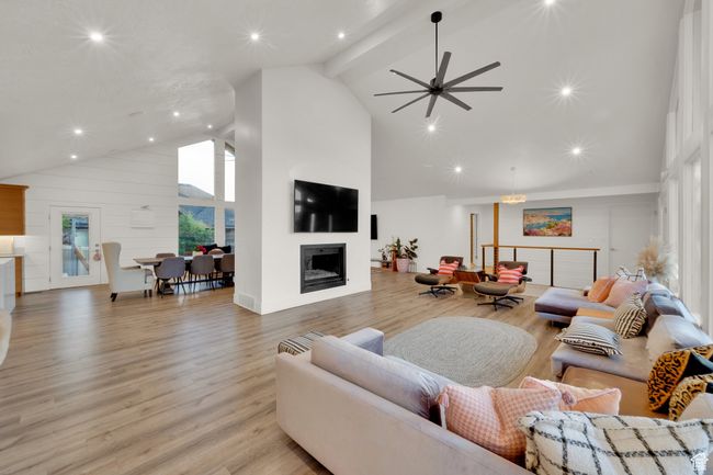 Living room featuring high vaulted ceiling, a fireplace, light wood-style floors, ceiling fan, and recessed lighting | Image 13