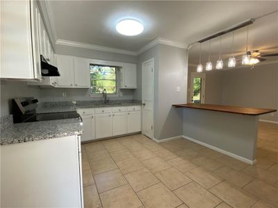 Kitchen featuring hanging light fixtures, kitchen peninsula, sink, white cabinetry, and stainless steel electric range oven | Image 3