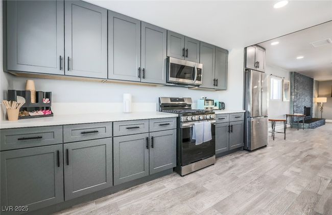 Kitchen featuring stainless steel appliances, gray cabinets, light wood-style floors, recessed lighting, and light countertops | Image 21