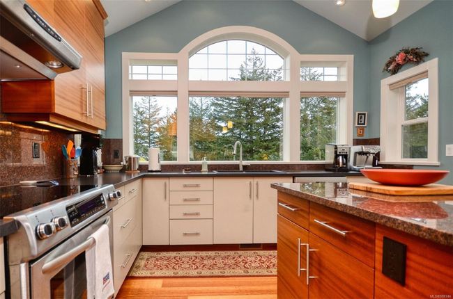 Kitchen featuring stainless steel range with electric cooktop, sink, Island, and vaulted ceiling | Image 8