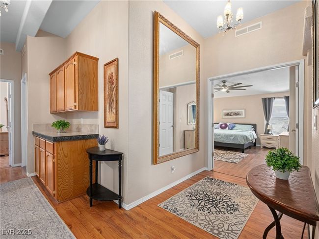 Corridor featuring a notable chandelier, visible vents, light wood-type flooring, and baseboards | Image 27