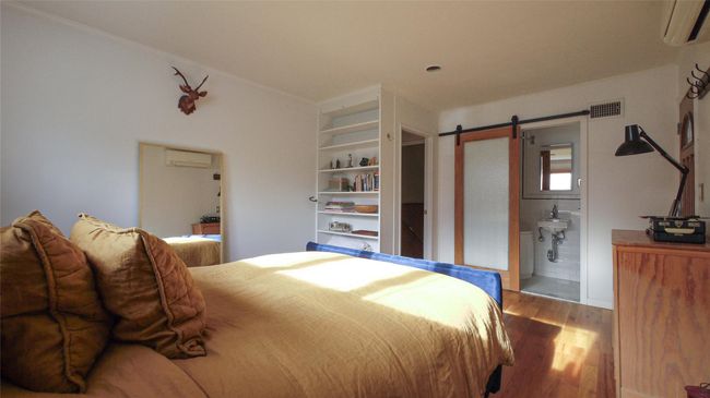 Bedroom with a wall mounted air conditioner, wood finished floors, a barn door, and ensuite bath | Image 15