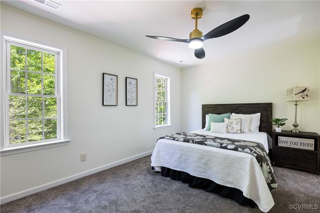 Carpeted bedroom with ceiling fan, baseboards, multiple windows, and visible vents | Image 22