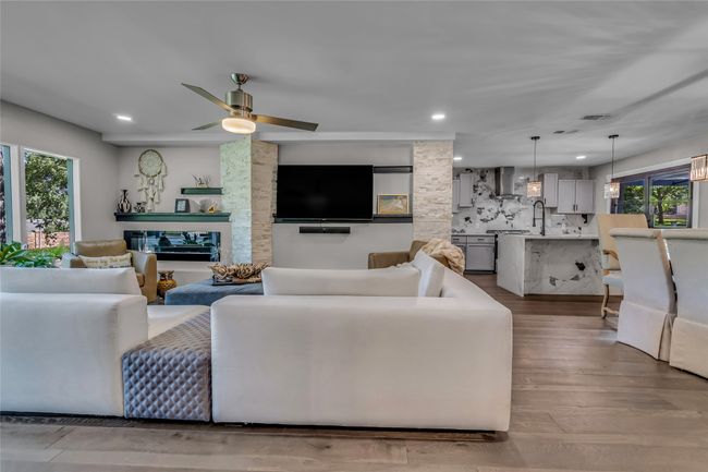Living room featuring wood finished floors, a large fireplace, ceiling fan, and recessed lighting | Image 8