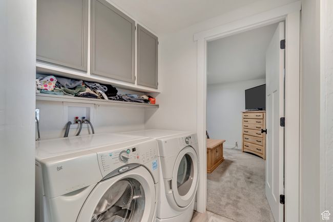 Washroom featuring light colored carpet, separate washer and dryer, and cabinet space | Image 11