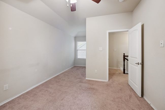 Unfurnished bedroom featuring light colored carpet, vaulted ceiling, and ceiling fan | Image 14