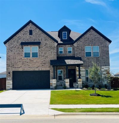 The Yale plan at The Colony is a beautiful two-story home with a long driveway, gorgeous cedar garage door, and lush front yard landscaping. | Image 1