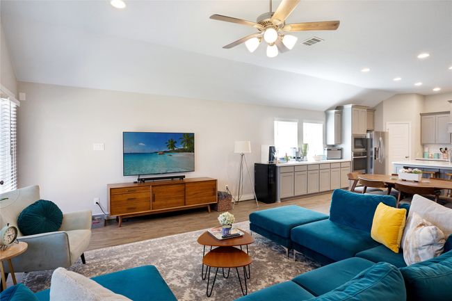 Living area featuring light wood-type flooring, lofted ceiling, recessed lighting, and a ceiling fan | Image 4