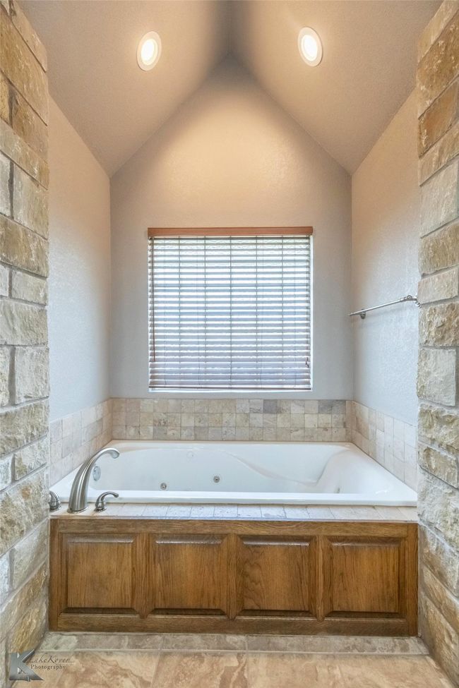 Full bath featuring lofted ceiling, a tub with jets, and healthy amount of natural light | Image 17