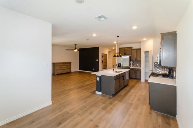 Kitchen featuring stainless steel fridge with ice dispenser, open floor plan, light countertops, tasteful backsplash, and light wood-style floors | Image 9