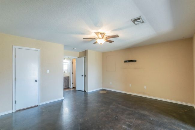 Unfurnished room featuring a textured ceiling, ceiling fan, visible vents, baseboards, and finished concrete floors | Image 15