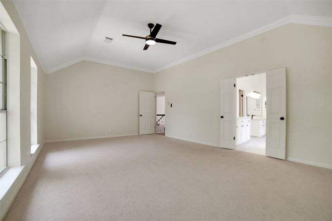 Unfurnished bedroom featuring lofted ceiling, light carpet, crown molding, baseboards, and a ceiling fan | Image 29