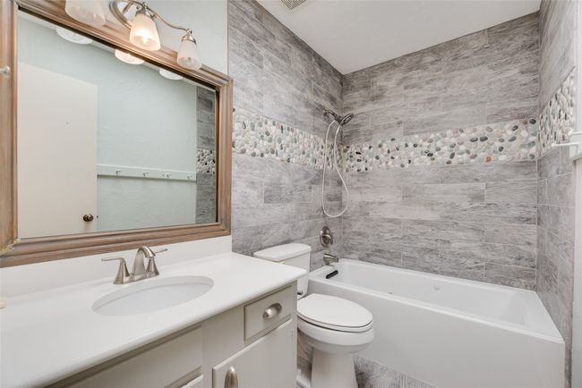 Bathroom with toilet, vanity, and shower / washtub combination | Image 21