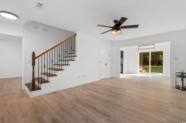 Unfurnished room with a tray ceiling, ceiling fan, light wood-style floors, and stairs | Image 13