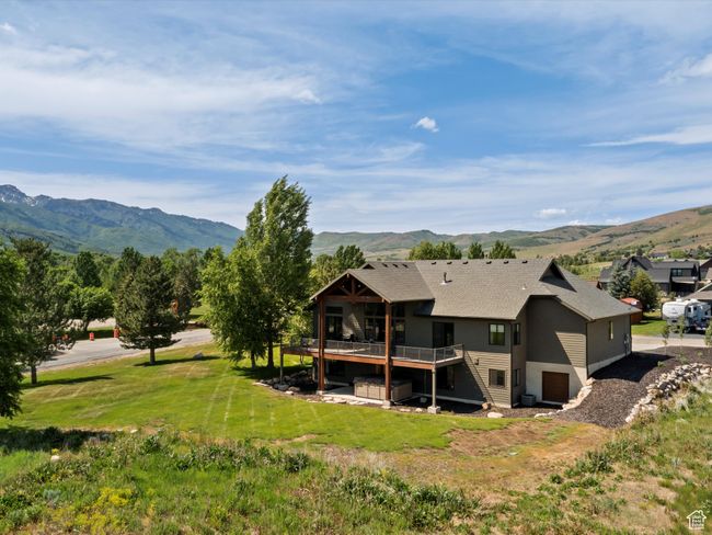 Back of house featuring a deck with mountain view, a shingled roof, and a lawn | Image 5