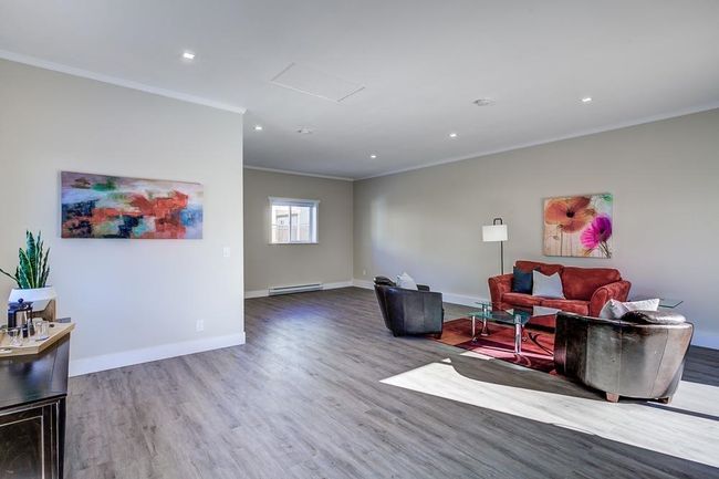 Living area with ornamental molding, baseboard heating, wood finished floors, baseboards, and recessed lighting | Image 20