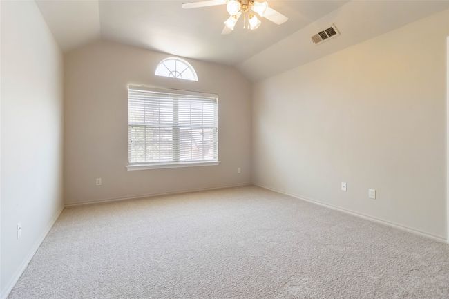 Carpeted spare room featuring visible vents, baseboards, a ceiling fan, and vaulted ceiling | Image 12