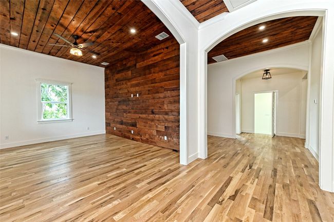 Living and Dining room with wood ceiling, light wood-style flooring, ceiling fan, wooden walls, and arched walkways | Image 11