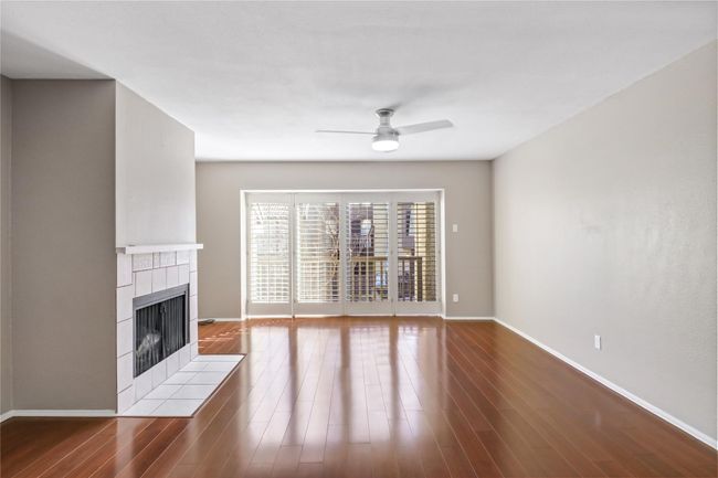 Unfurnished living room with a tile fireplace, a ceiling fan, baseboards, and wood finished floors | Image 8