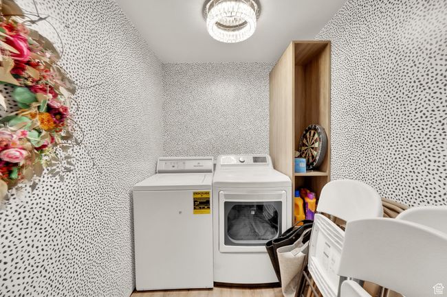 Washroom featuring washer and dryer, a chandelier, and light wood-type flooring | Image 25
