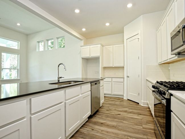 Kitchen with stainless steel appliances, recessed lighting, light wood-type flooring, and white cabinetry | Image 9