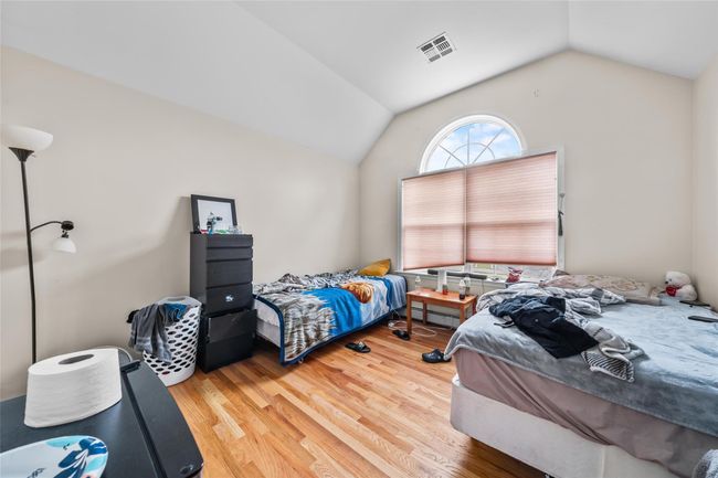 Bedroom featuring wood finished floors, vaulted ceiling, and visible vents | Image 31