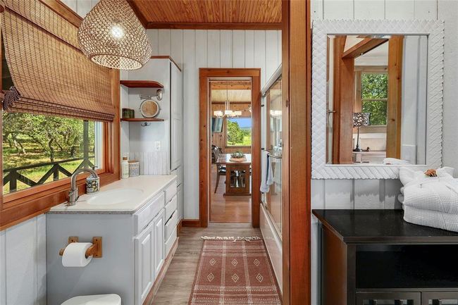 Bathroom featuring a wealth of natural light, wood finished floors, an inviting chandelier, and vanity | Image 21