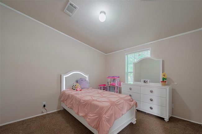 The room features a well-made bed adorned with decorative pillows and a stylish duvet cover, complemented by a hardwood floor that adds warmth to the space. | Image 20