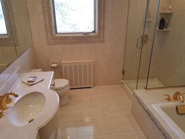 Full bath featuring toilet, radiator, a stall shower, and a sink | Image 10