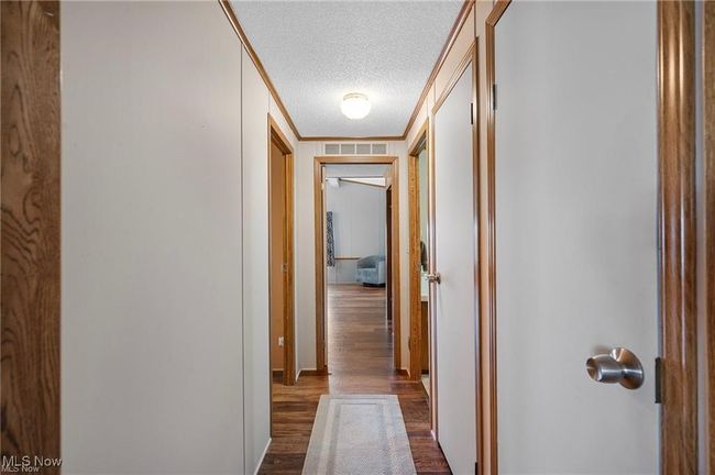 Corridor with ornamental molding, a textured ceiling, and dark wood-style flooring | Image 12