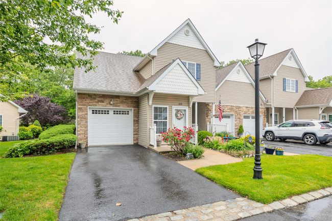 View of front of house featuring stone siding, an attached garage, a front lawn, driveway, and roof with shingles | Image 28
