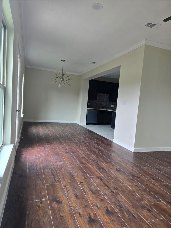 Empty room featuring a chandelier, wood-type flooring, crown molding, and baseboards | Image 5