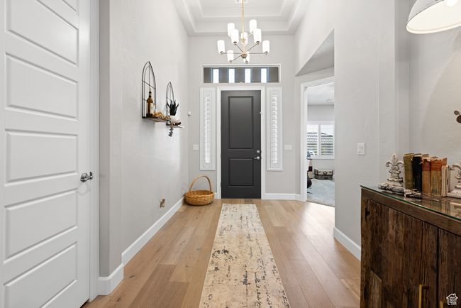 Foyer entrance featuring light wood-type flooring, a chandelier, a raised ceiling, and crown molding | Image 22