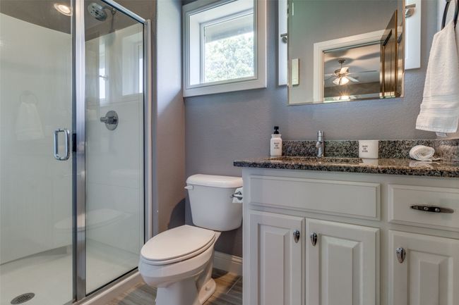 Bathroom featuring walk in shower, ceiling fan, hardwood / wood-style flooring, vanity, and toilet | Image 17