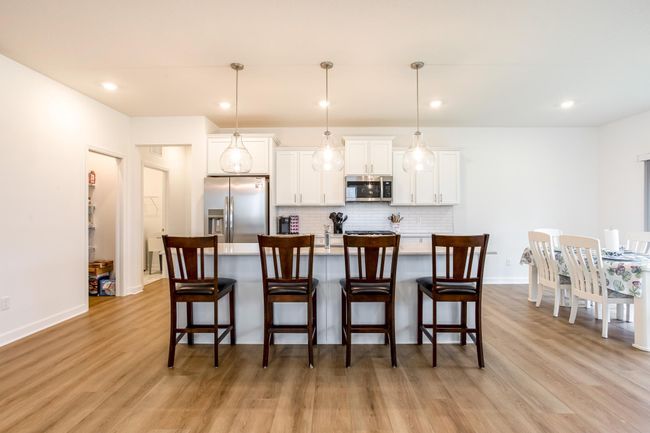 Four-seat island provides a perfect casual dining spot or prep space beneath statement pendant lights. | Image 8