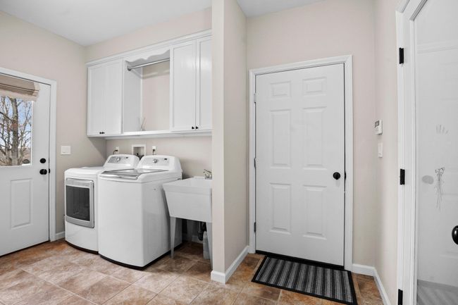 This bright and functional first level laundry room offers garage and pantry access, with built-in cabinetry and exterior entry for everyday convenience. | Image 6