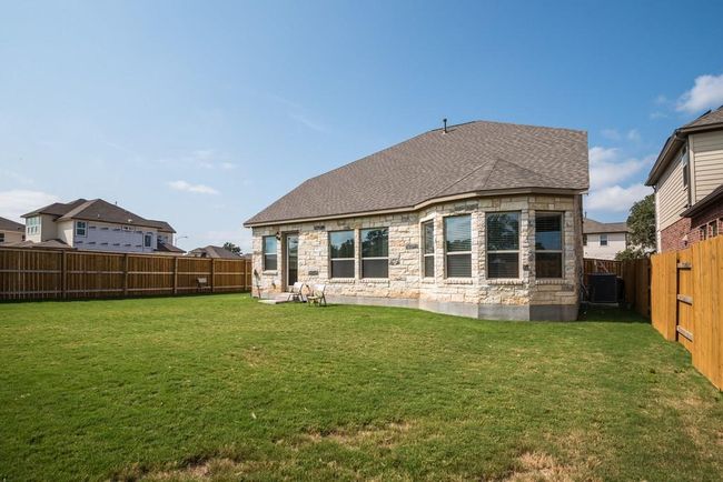 Rear view of house with a lawn, a shingled roof, a fenced backyard, and stone siding | Image 27