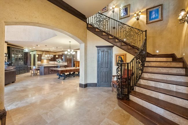 Entryway featuring arched walkways, a chandelier, stairway, ornamental molding, and a towering ceiling | Image 5