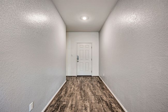 Doorway with dark wood finished floors, baseboards, and a textured wall | Image 4