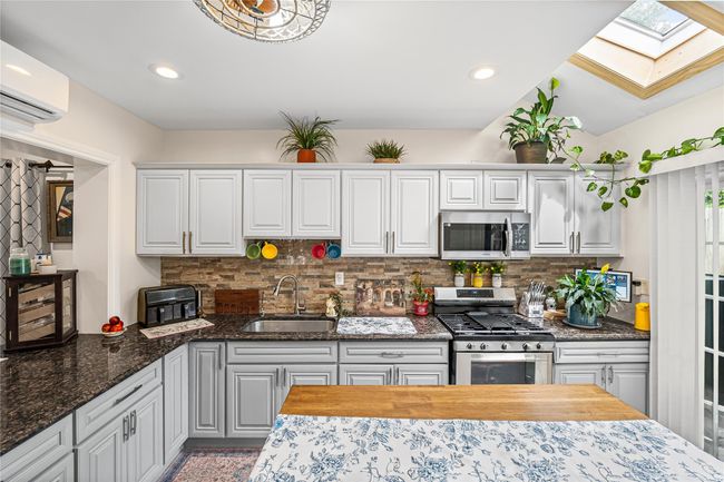 Kitchen with appliances with stainless steel finishes, a sink, a skylight, tasteful backsplash, and recessed lighting | Image 11